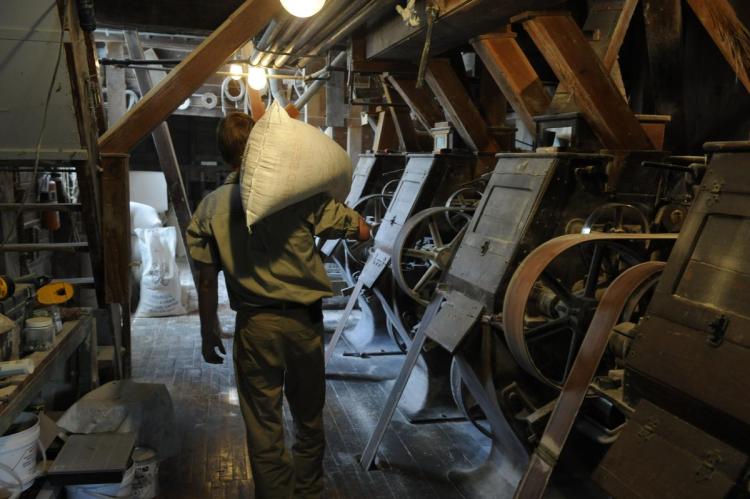 Photo of worker with sack over shoulder walking past machinery